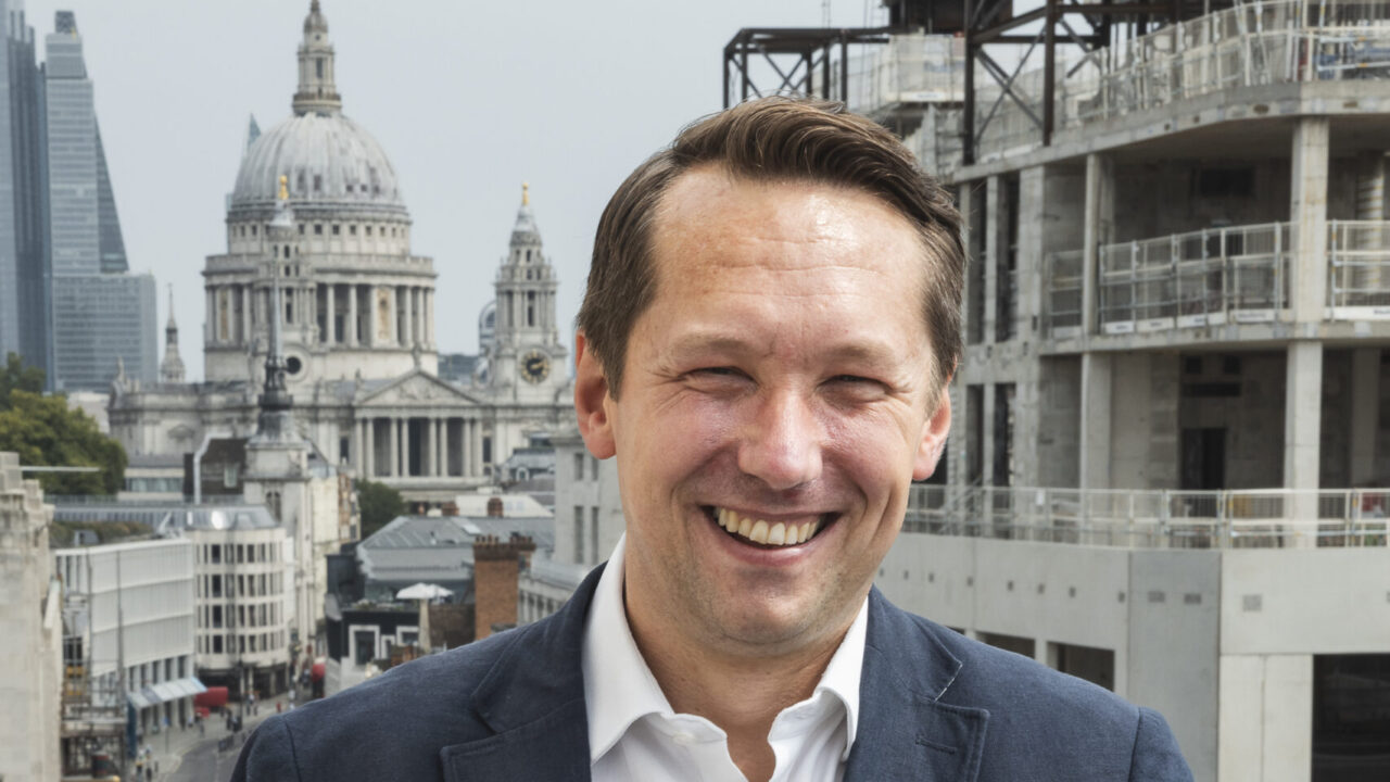 Picture of Stephen White standing outside on a balcony on Fleet Street with construction work and St Pauls Cathedral in the background.