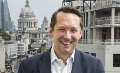Picture of Stephen White standing outside on a balcony on Fleet Street with construction work and St Pauls Cathedral in the background.
